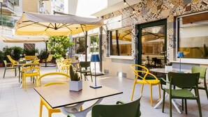 An outdoor dining area with yellow and green chairs, tables, and umbrellas. - Adesso Hotel (Rome)