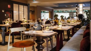 A restaurant with multiple tables set for dining, chairs, and a long bench for seating. - Adesso Hotel (Rome)