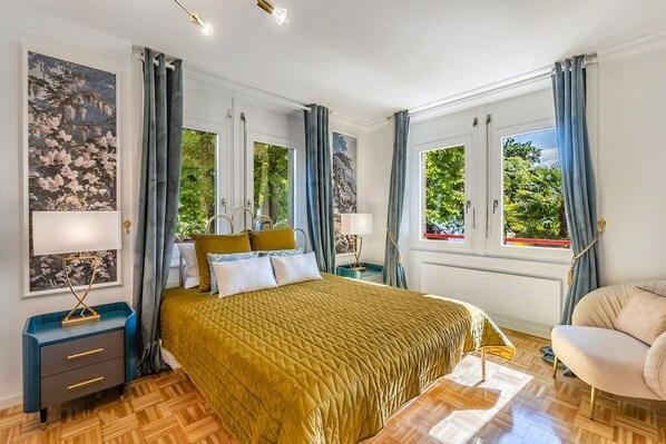 Ein helles Schlafzimmer mit einem großen Bett, zwei Nachttischen und einem Sessel.