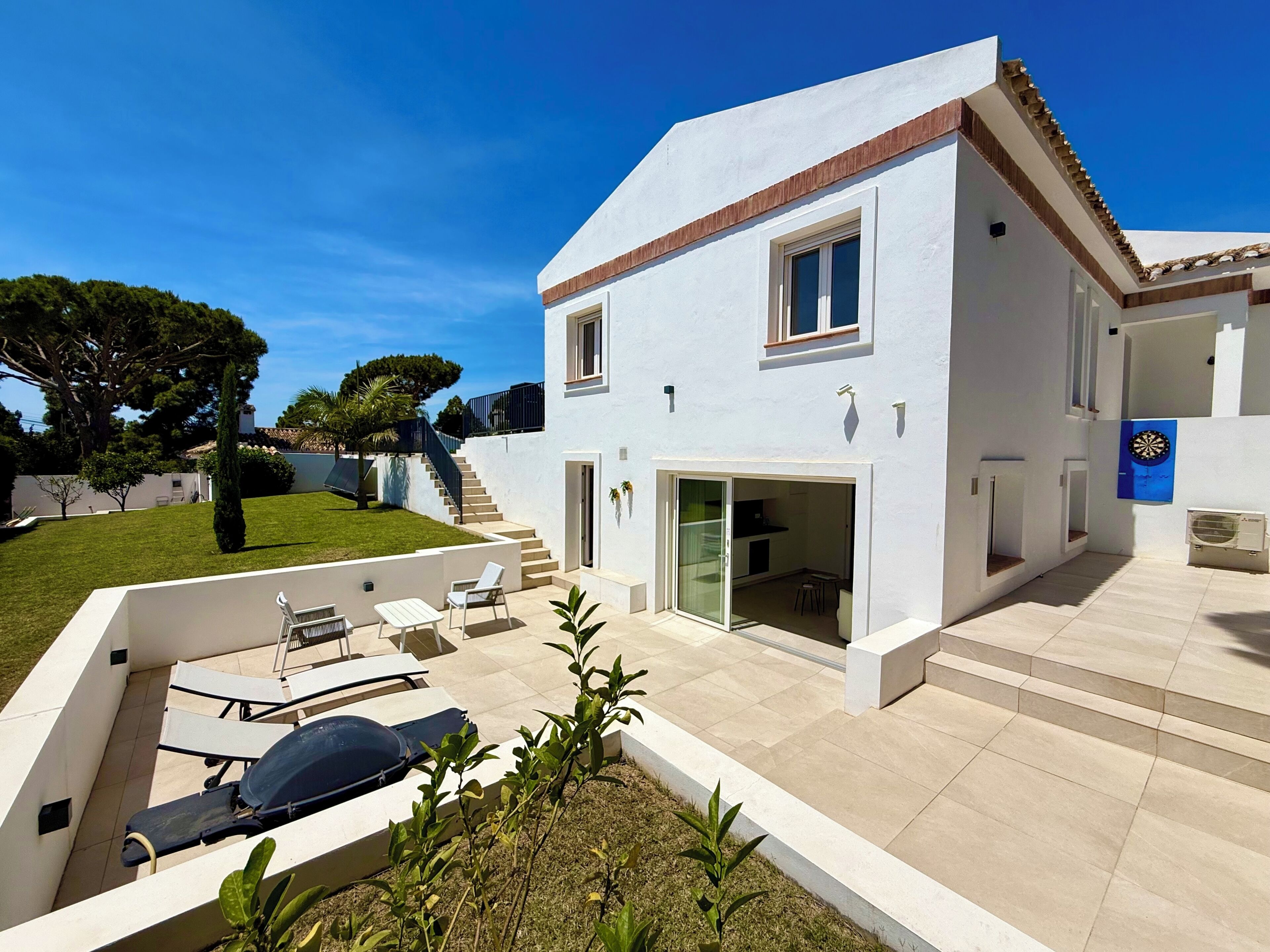 Une maison moderne à deux étages, dotée d’un patio, d’un espace salon extérieur et d’un escalier menant à l’étage supérieur.
