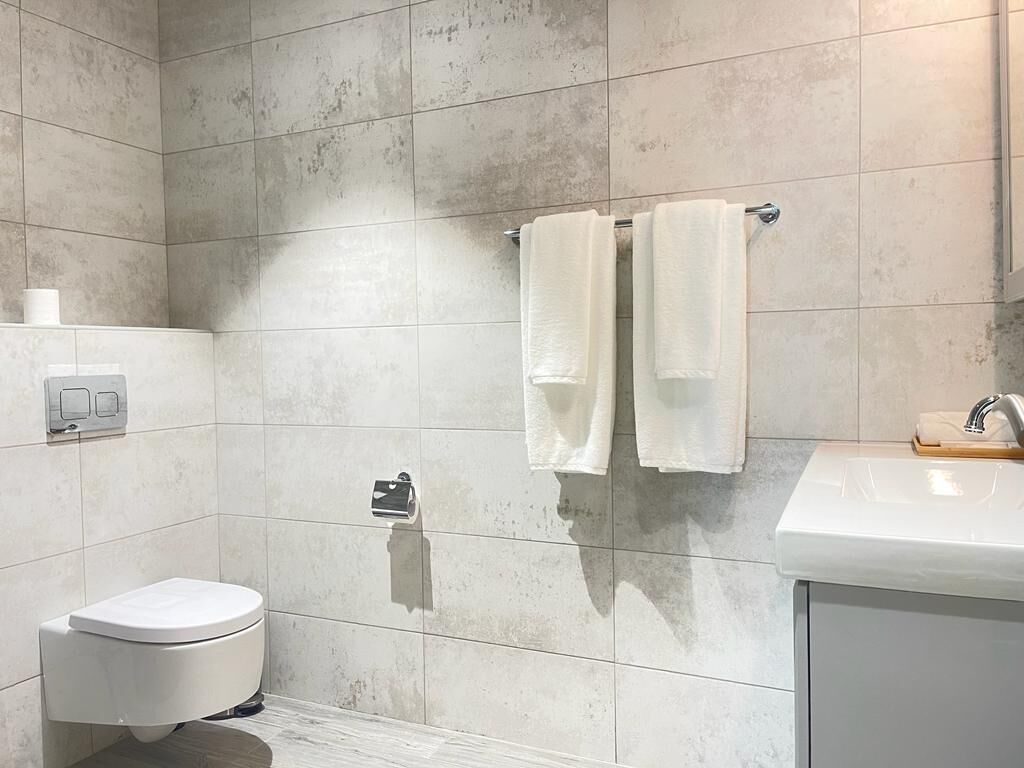 Un bagno con un water, un lavandino e due asciugamani appesi a un porta-asciugamani.