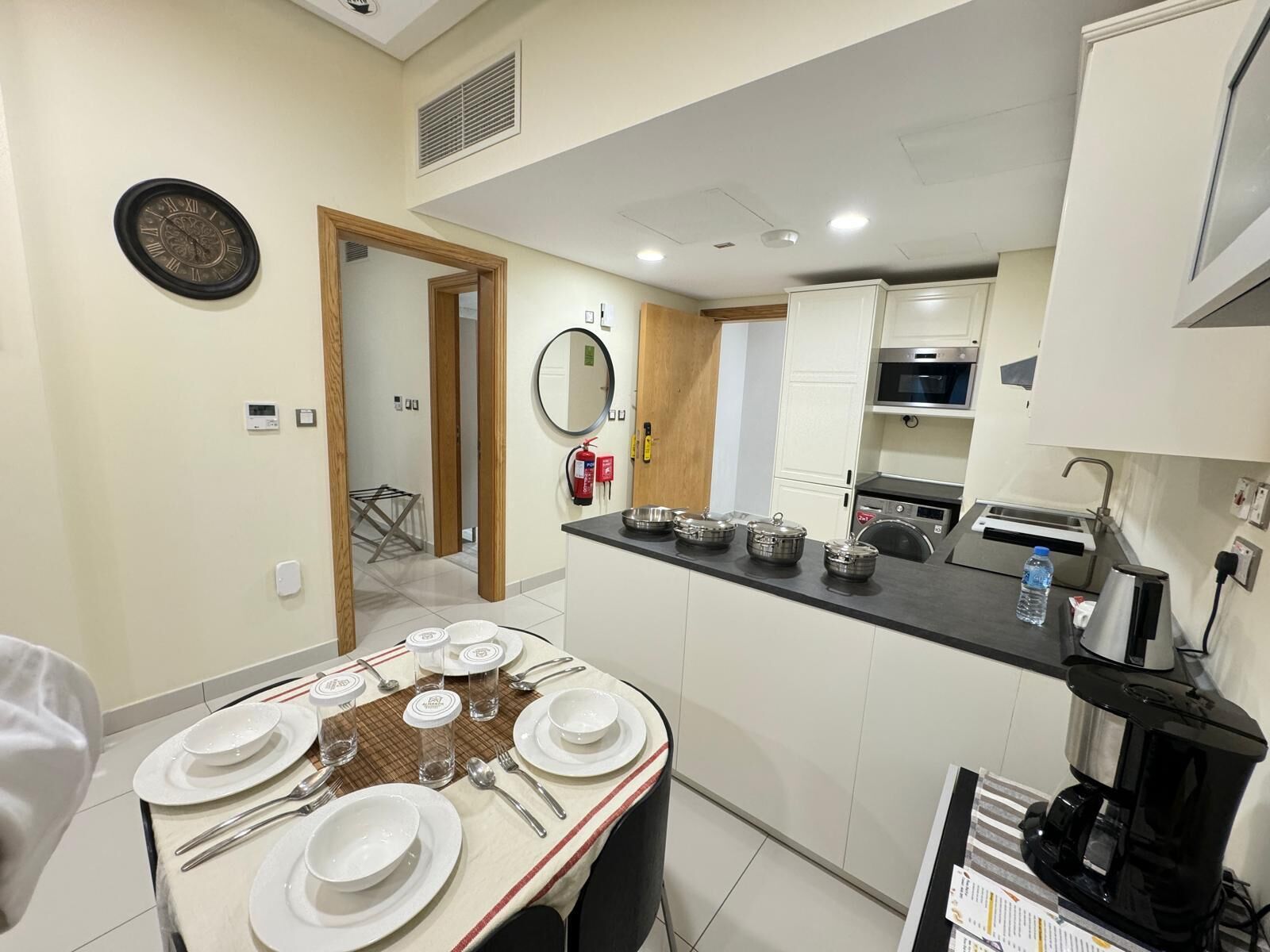 Una cocina moderna con comedor, equipada con cafetera, microondas y electrodomésticos de acero inoxidable.