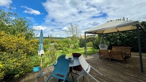 An outdoor patio with a table and chairs, a hanging chair, and a covered seating area. - La Mandragora - Atelier d’art et poésie (Vernon)