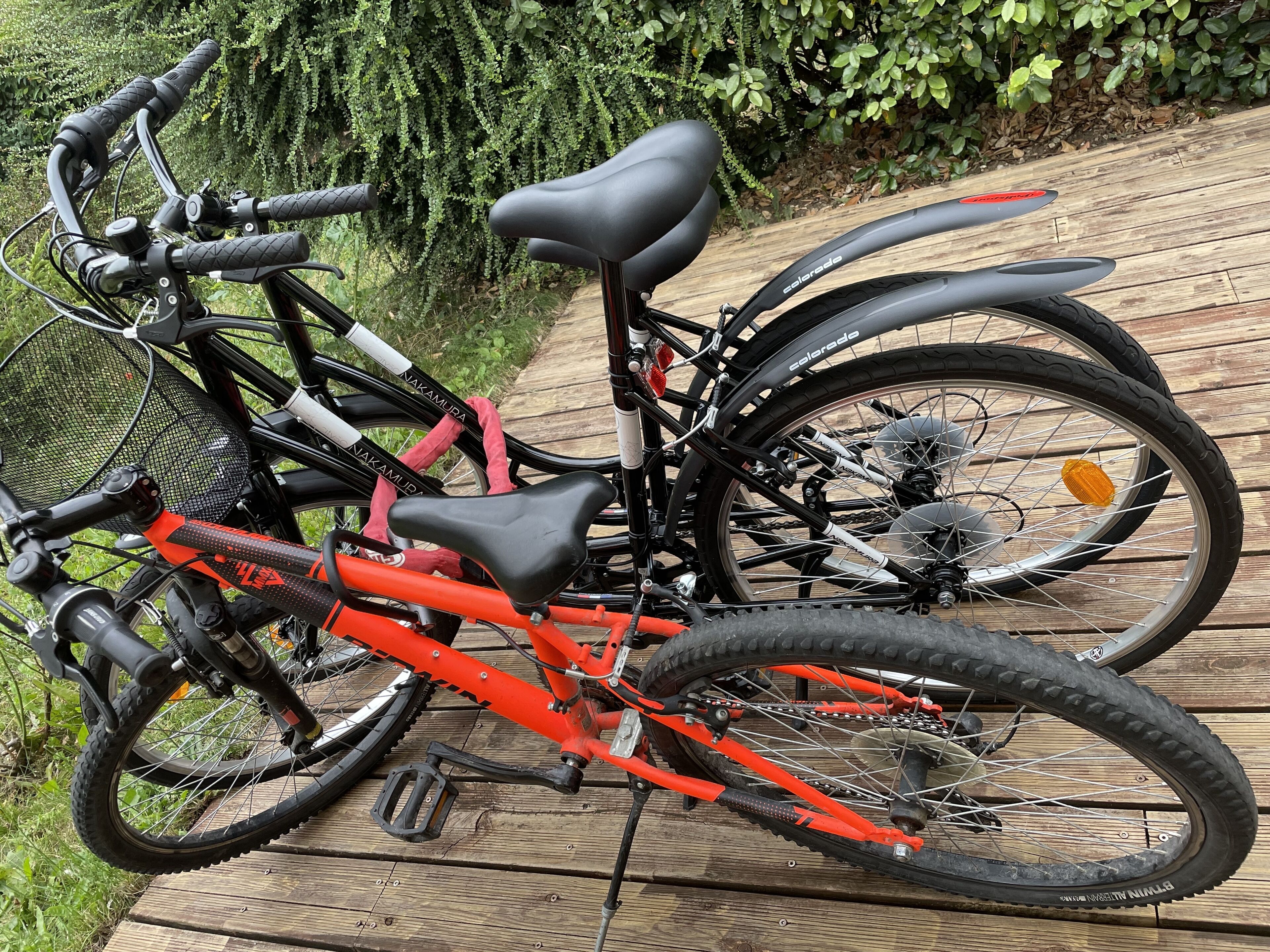 Una bicicleta con estructura negra y naranja, asiento negro y una cesta delantera.