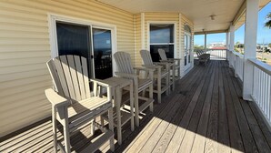 A covered porch with wooden chairs and a sliding glass door. - Paradise Falls here! 4 BR, Elevator, Pool, across the street from beach (ST GEORGE ISLAND)