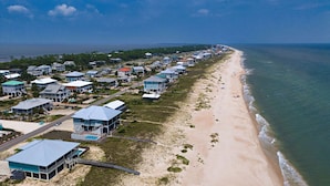 Een woongebied aan de kust met huizen direct aan het strand, een promenade en een helder uitzicht op de oceaan.