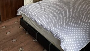 Ein Schlafzimmer mit Bett, Schrank, Fenster mit Jalousien und einer Tür.