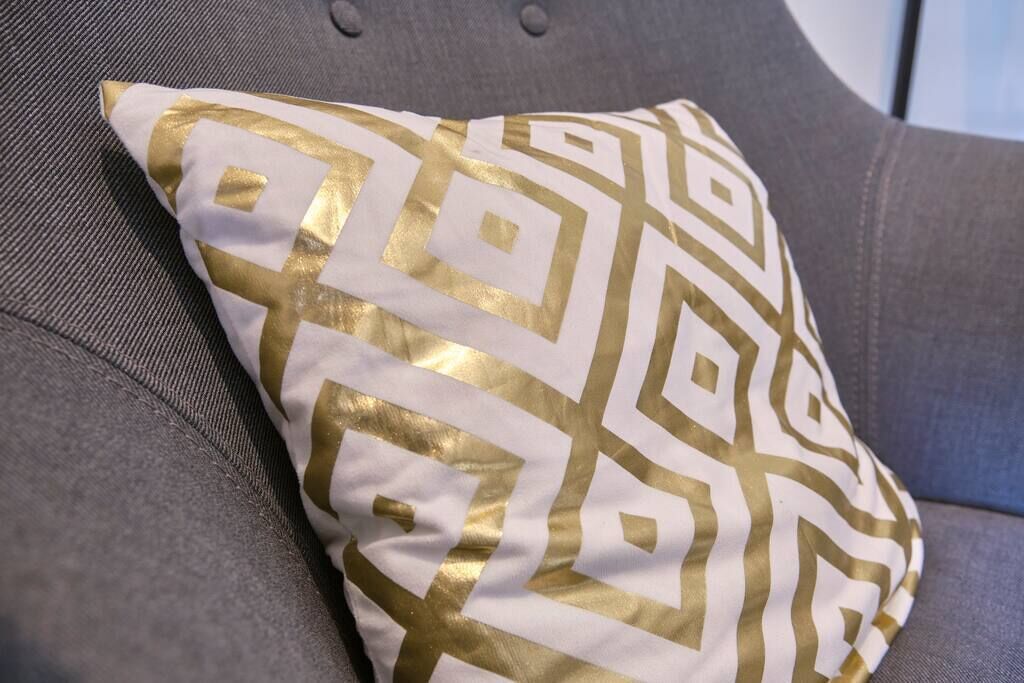 Ein Kissen mit geometrischem Muster auf einer grauen Couch.
