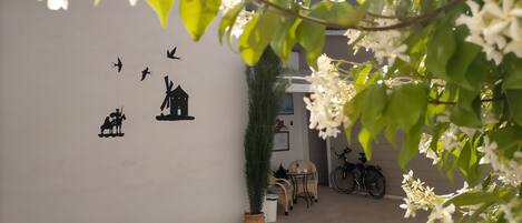 A courtyard with a wall decorated with black silhouettes, a potted plant, and bicycles.