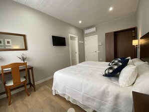 A bedroom with a bed, a desk, a chair, and a television.