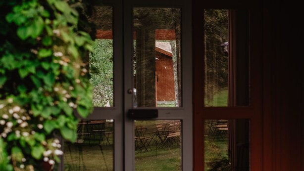 Une entrée d’immeuble avec une porte en verre, un banc et une vue sur un jardin.