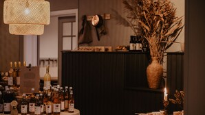 Une table avec différentes bouteilles de vin, une bougie et un vase contenant des plantes séchées.