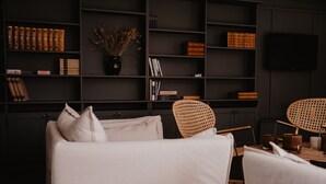 Un salon moderne comprenant un canapé, des fauteuils, une table basse et une bibliothèque remplie de livres et d’objets décoratifs.