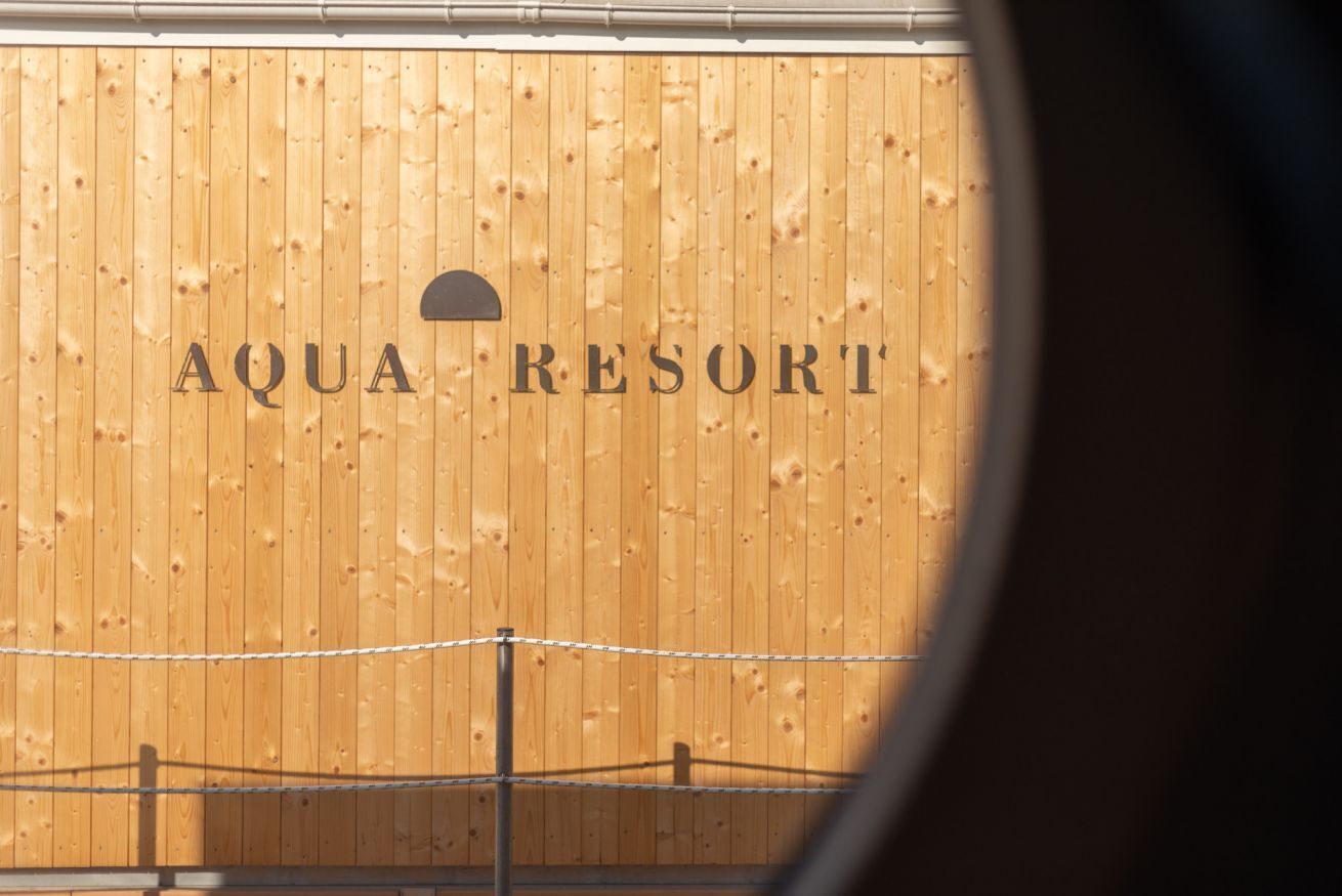 Un muro di legno con la scritta "AQUA RESORT" e una parte di una recinzione.