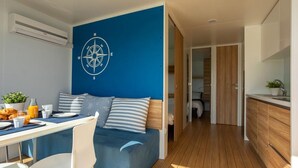 Une chambre moderne avec un mur d’accent bleu, un motif de boussole, un coin repas où le petit-déjeuner est servi, et un plancher en bois.