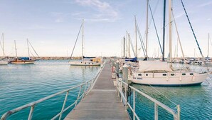 Un port de plaisance où de nombreux voiliers sont amarrés le long d’une jetée en bois.