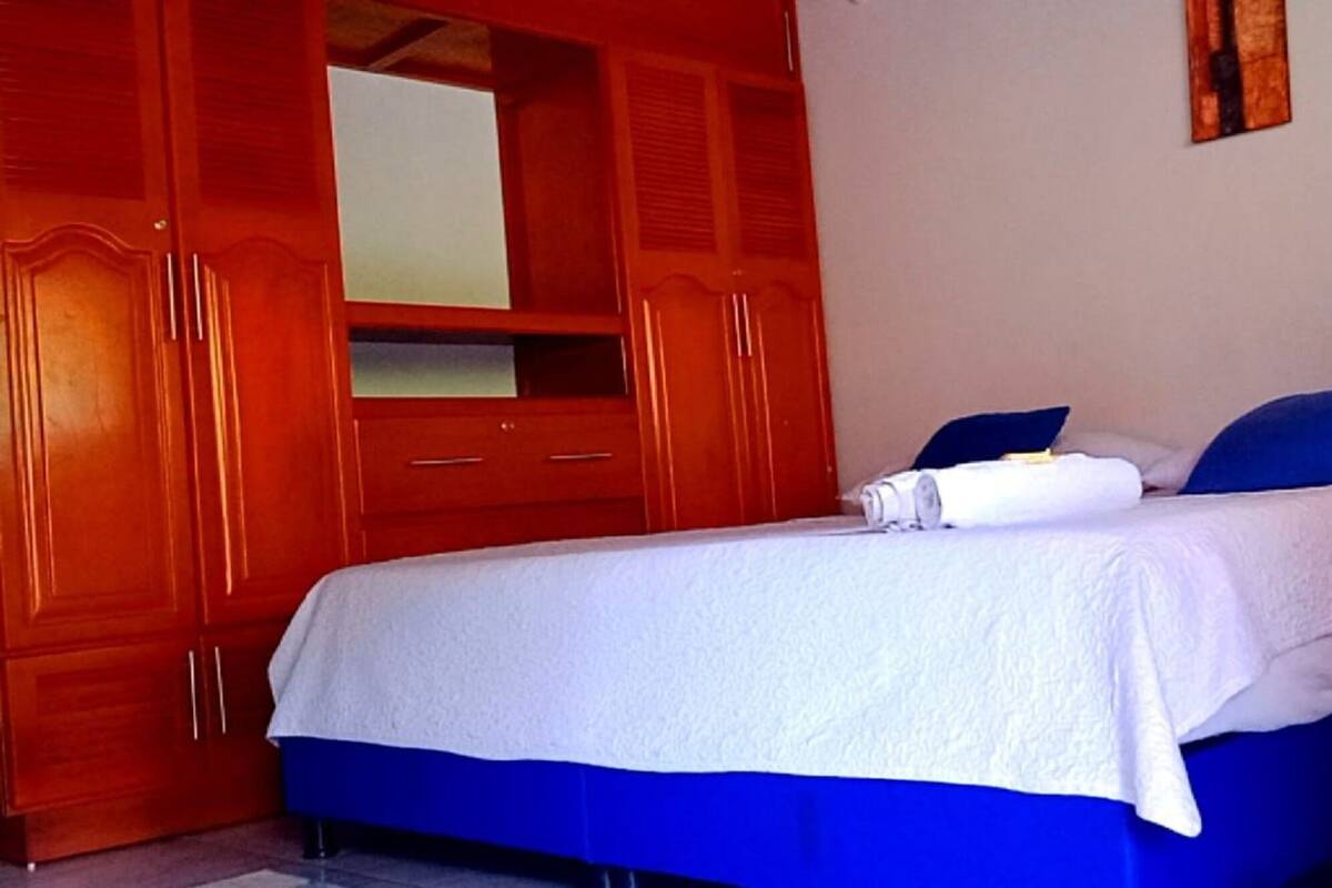 A bedroom with a bed, a wooden wardrobe, and a mirror.