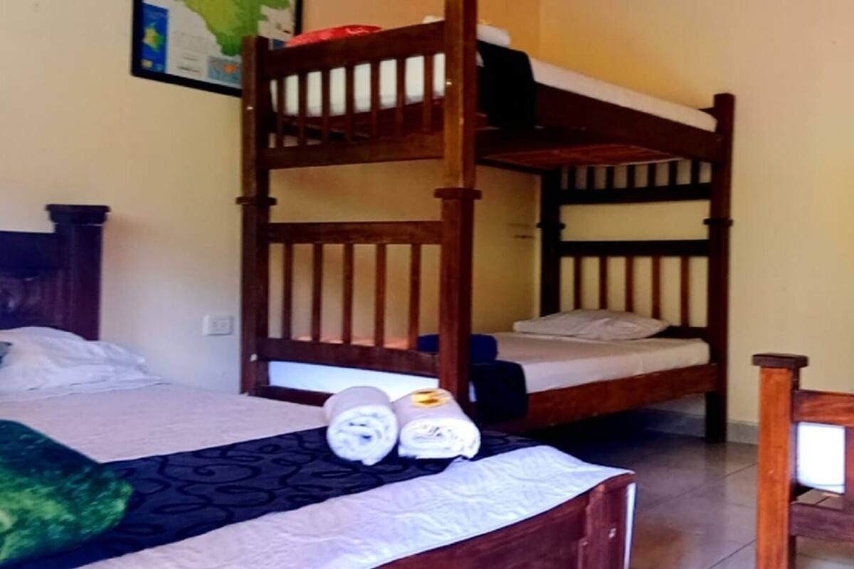 A room with two bunk beds, a single bed, and a wooden headboard.