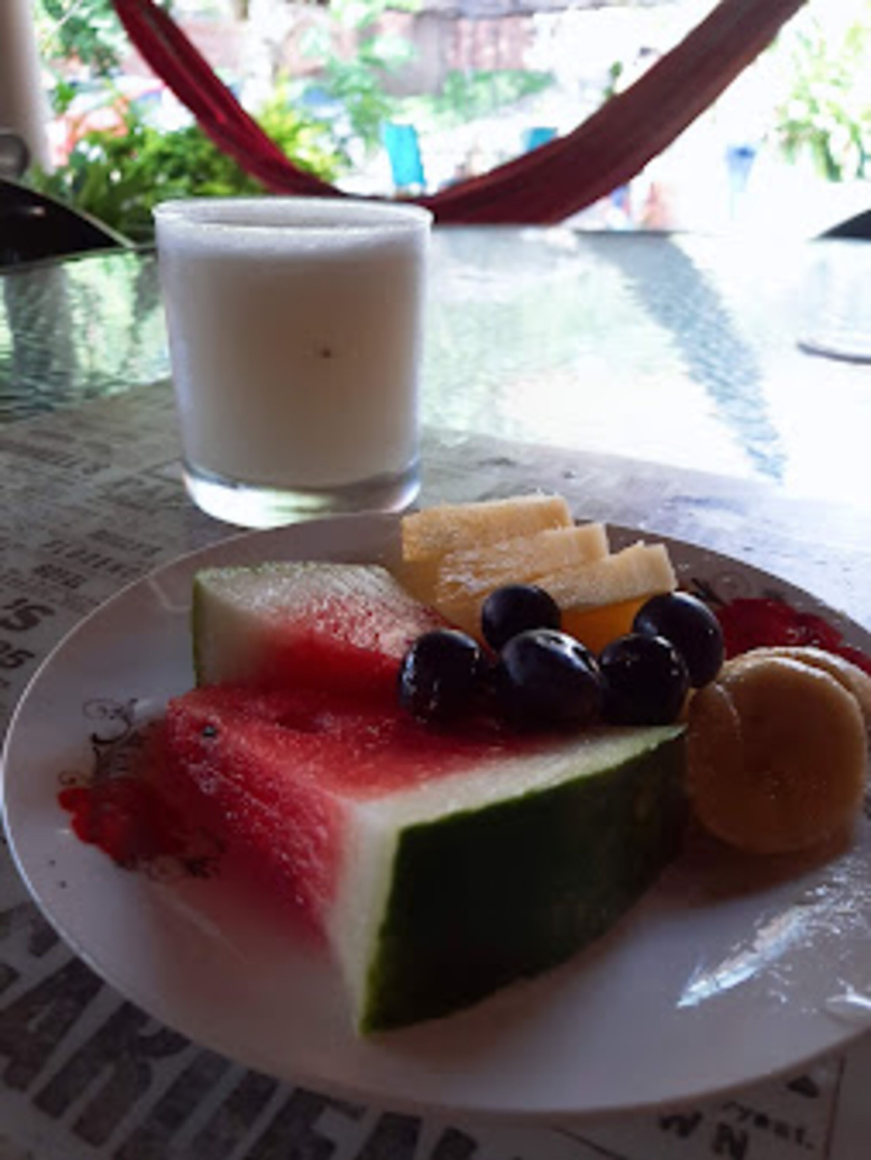 A plate with watermelon, blueberries, and a slice of cake on a table.
