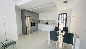 Una cocina moderna con electrodomésticos de acero inoxidable, una mesa de comedor de vidrio y sillas negras.