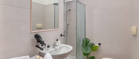 A modern bathroom with a glass-enclosed shower, a sink with a mirror, and a toilet.