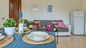 Un comedor con una mesa preparada para dos personas, una botella de vino y una planta en maceta.