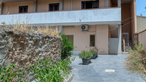 Un edificio de dos pisos con balcón, aire acondicionado y plantas en macetas.