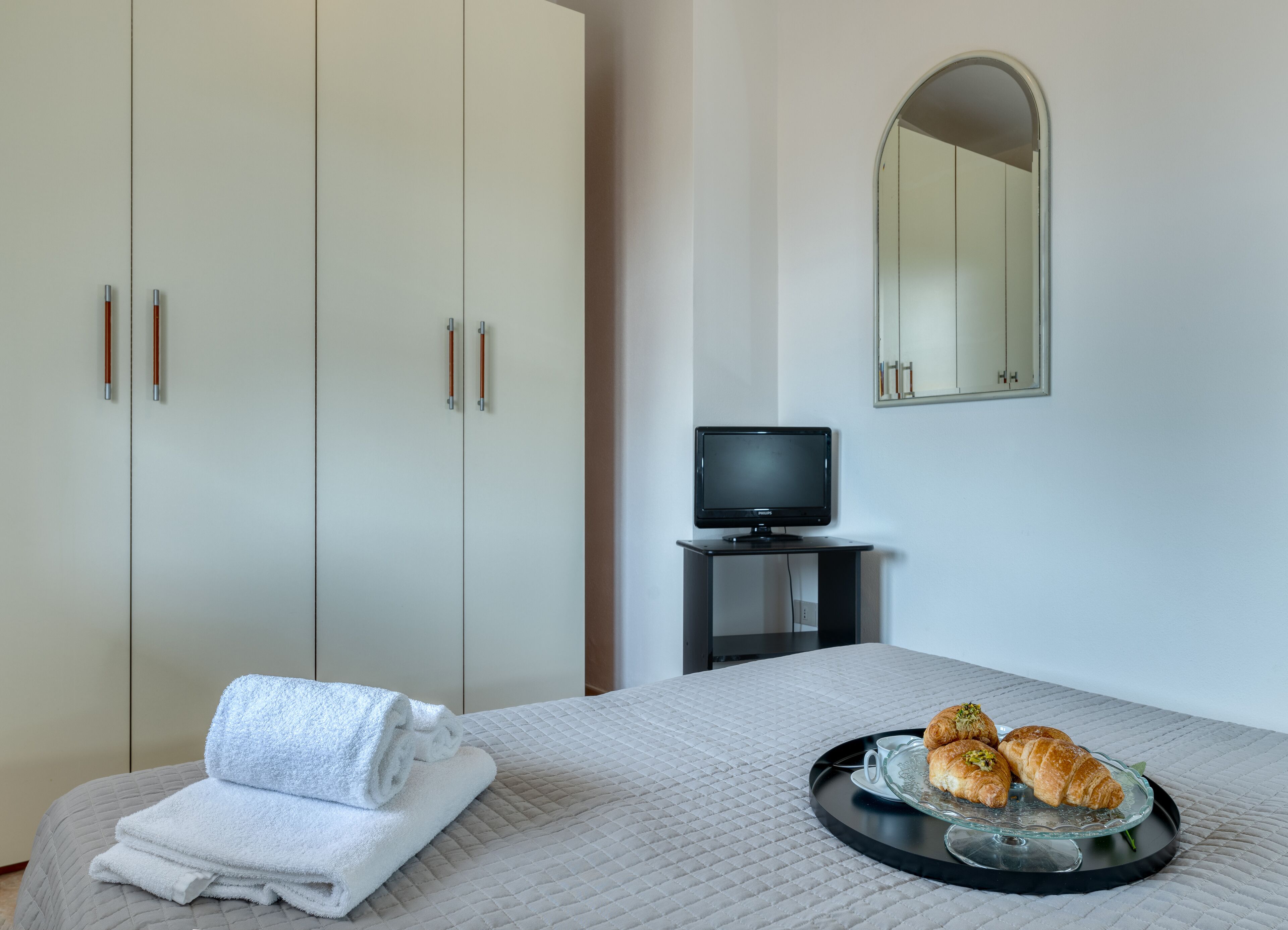 A bedroom with a bed, a TV, and a tray with pastries.