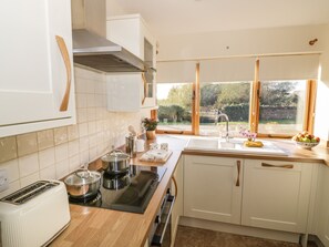 Una cocina moderna con armarios blancos, una estufa integrada y un amplio ventanal con vistas al jardín.