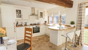 A modern kitchen with white cabinetry, a central island, and a dining area with a chair and table.