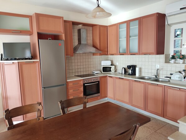 A kitchen with wooden cabinets, a refrigerator, a microwave, a toaster, a coffee maker, and a sink.