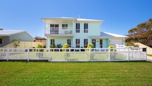 A two-story house with a balcony, a garage, and a white picket fence.