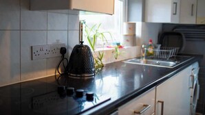 A kitchen with a black kettle, a window with plants, and a sink. - George's City Centre Apartment - Salisbury (Salisbury)