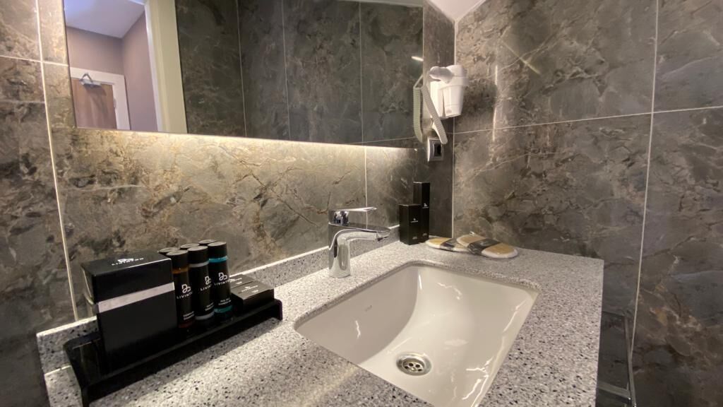Ein modernes Badezimmer mit einer Granittheke, einem weißen Waschbecken und einer Handbrause.
