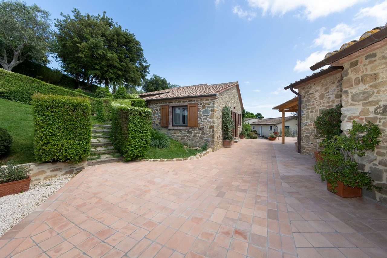 A stone building with a tiled roof, a paved pathway, and a well-maintained garden.