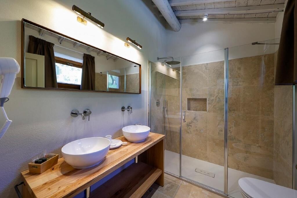 Een moderne badkamer met twee wasbakken, een grote spiegel en een douche met glazen wanden.