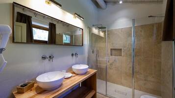 Un baño moderno con dos lavamanos, un espejo grande y una ducha con mampara de vidrio.