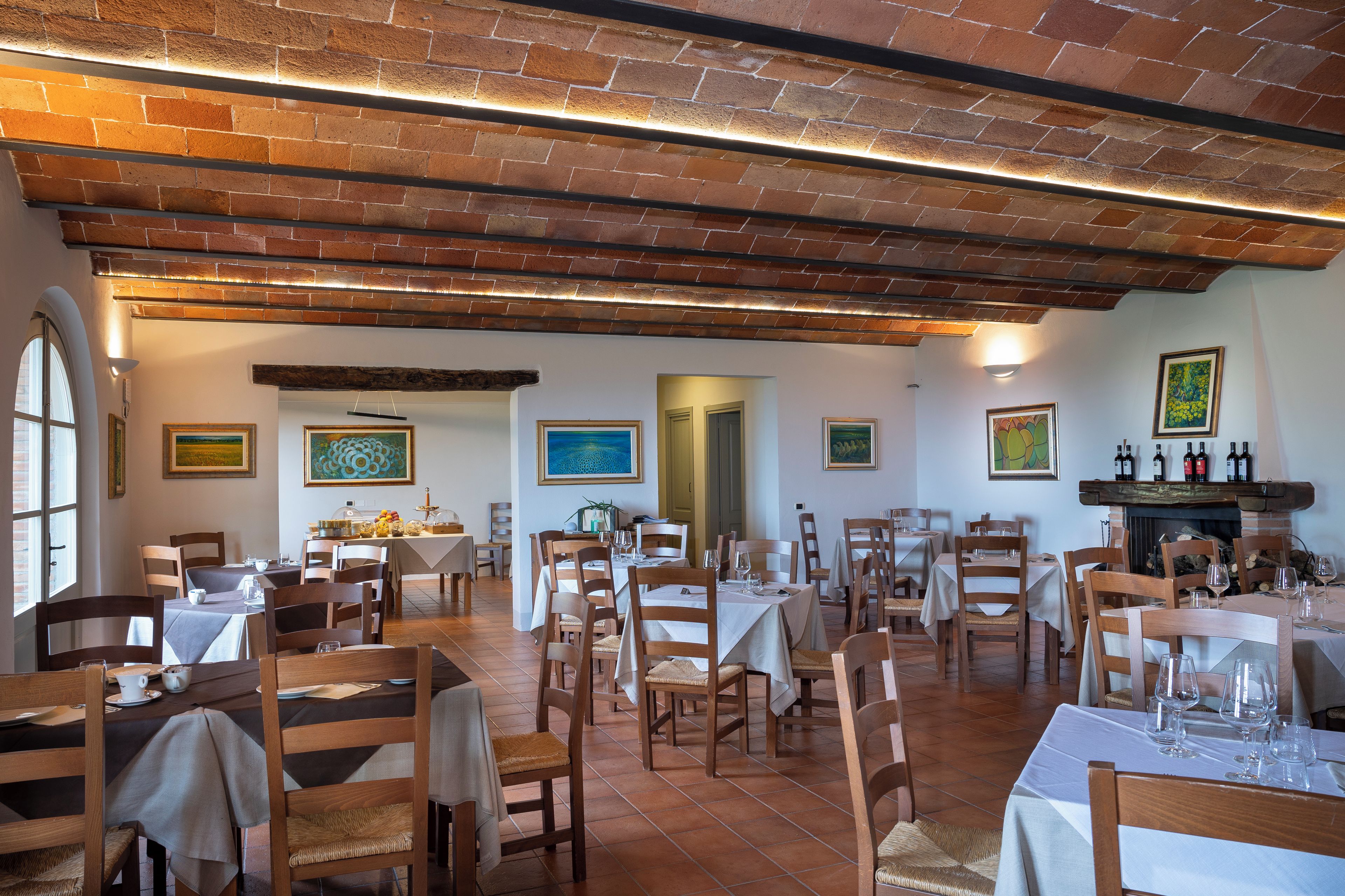 A restaurant with brick walls, wooden beams, and multiple dining tables with chairs.