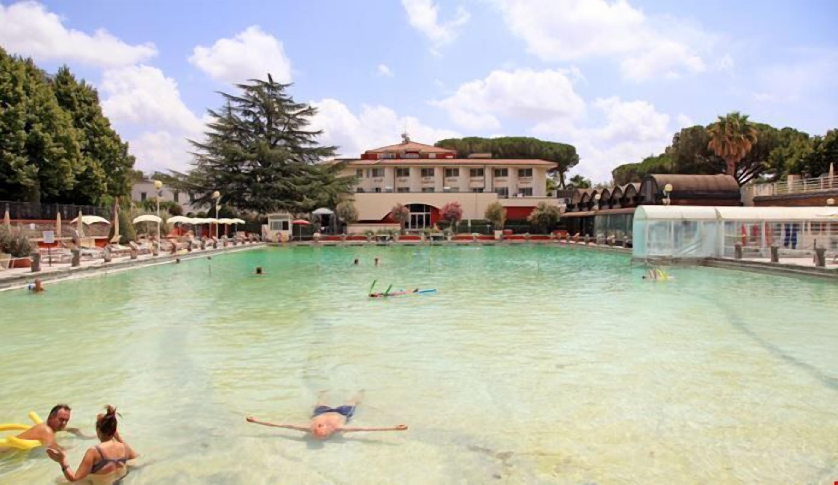 A large outdoor swimming pool with clear water, surrounded by lounge chairs and umbrellas.