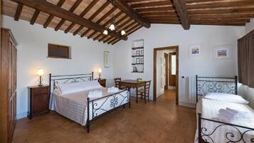 A bedroom with two beds, a wooden ceiling, a small table, and a chair.