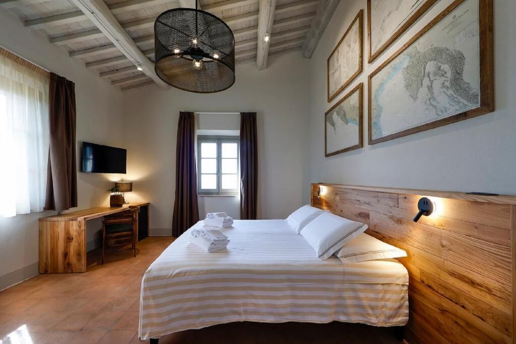 Una habitación de hotel con cabecera de madera, cama con ropa de cama a rayas, escritorio con lámpara y obras de arte en las paredes.