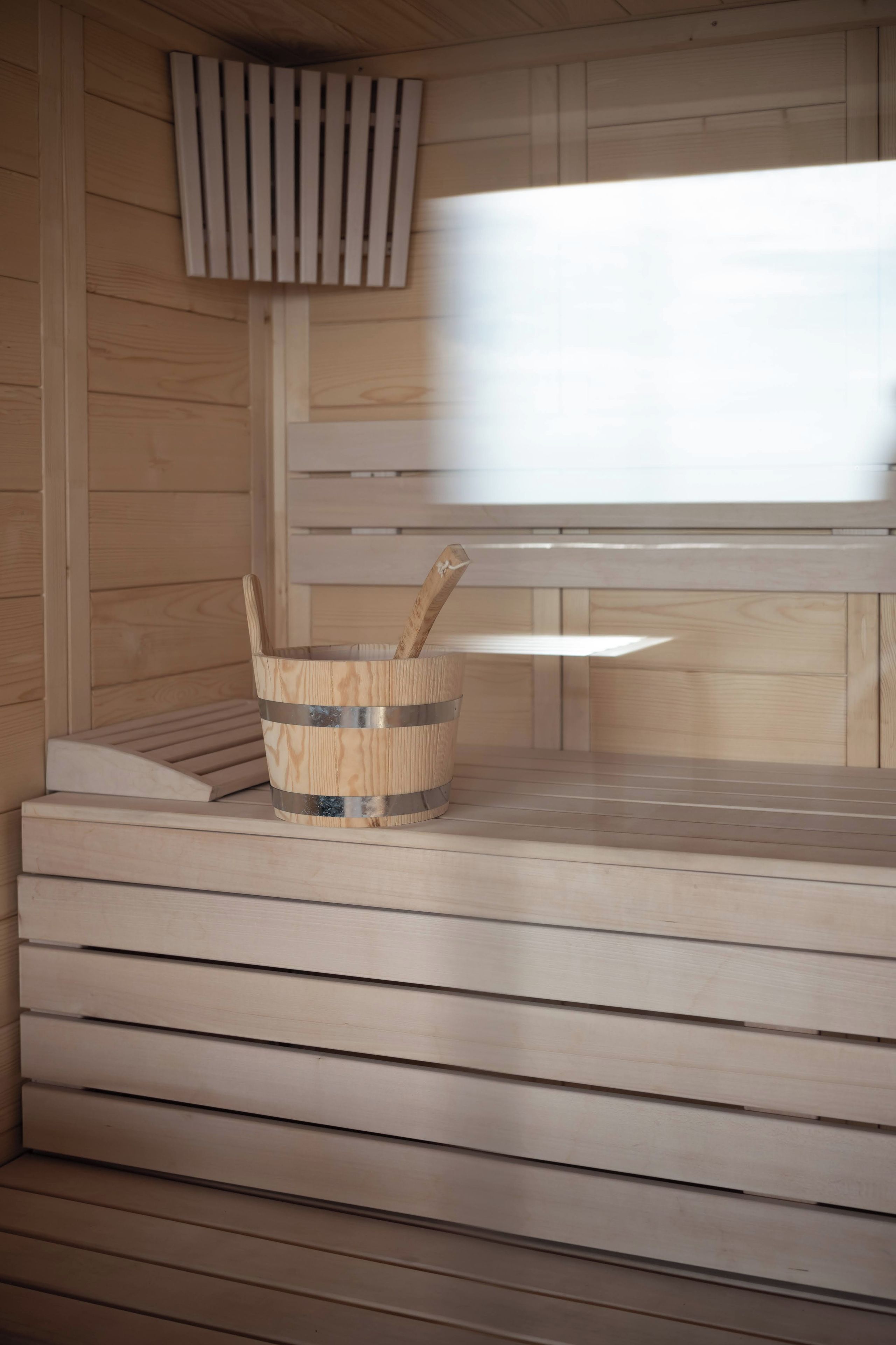A wooden sauna with a bench and a wooden bucket.