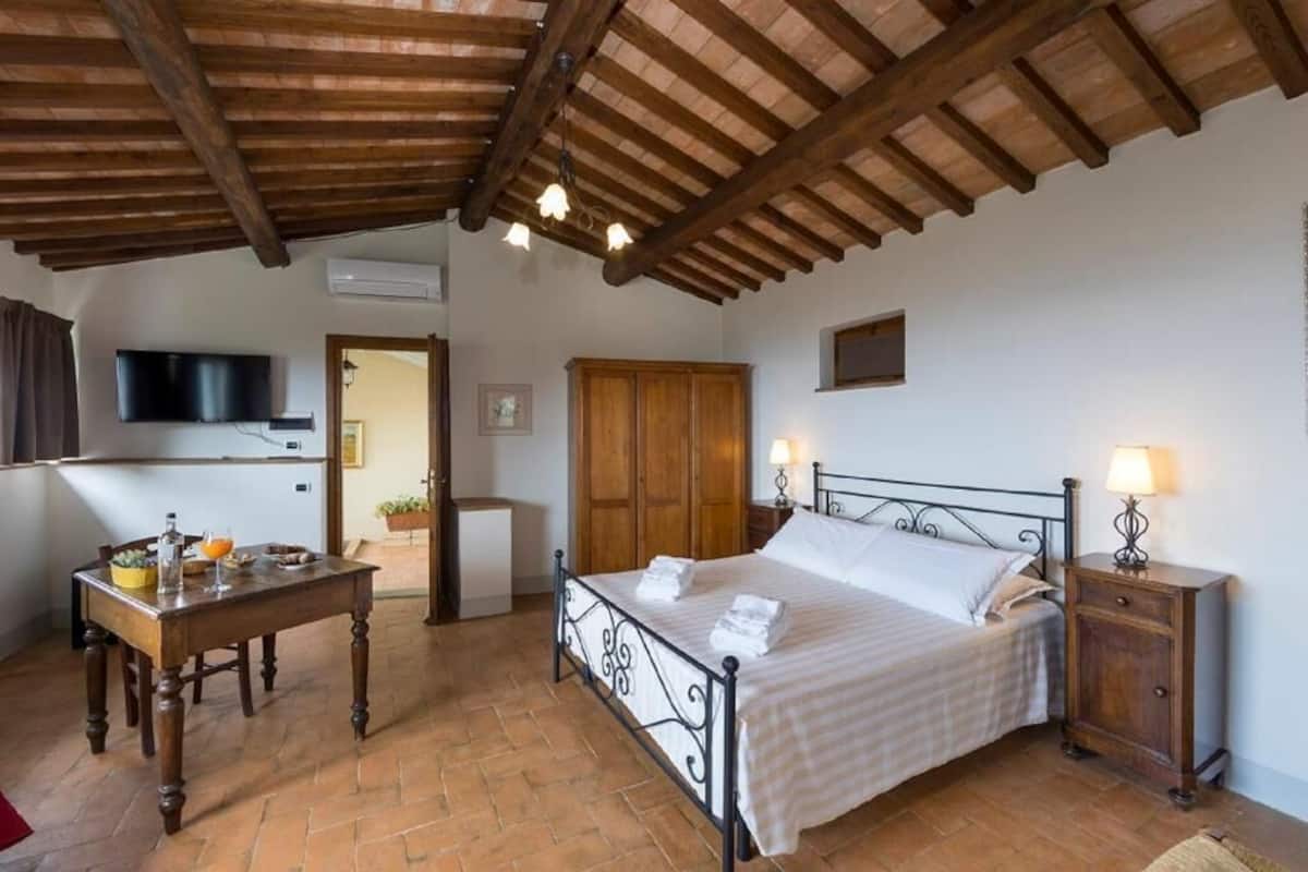 Een slaapkamer met een bed, nachtkastje en een aan de muur bevestigde televisie.