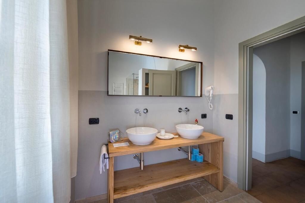 A modern bathroom with two sinks, a large mirror, and a wooden vanity.