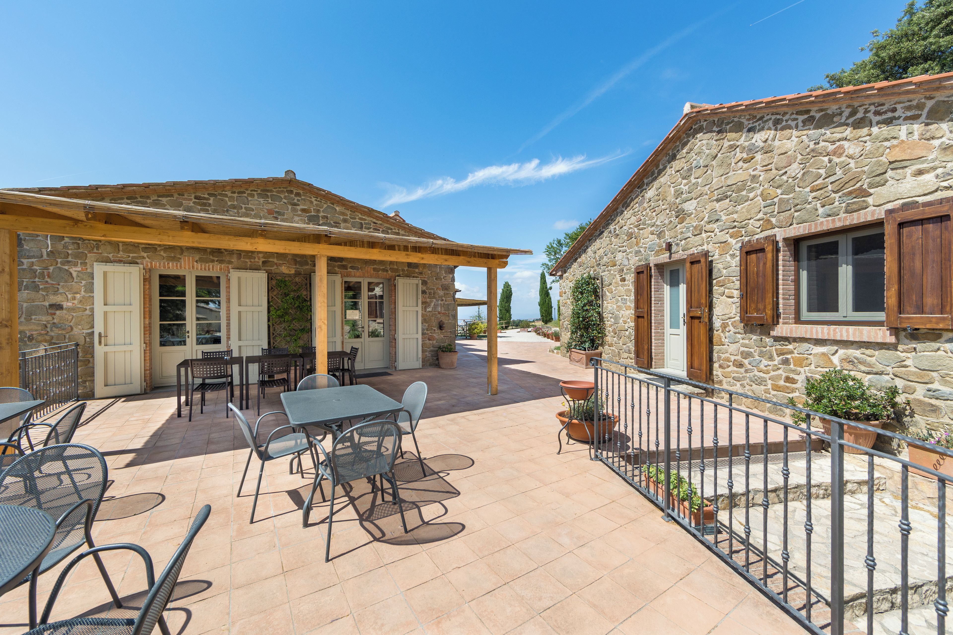 A stone building with a tiled patio, outdoor seating, and a view of the sea.