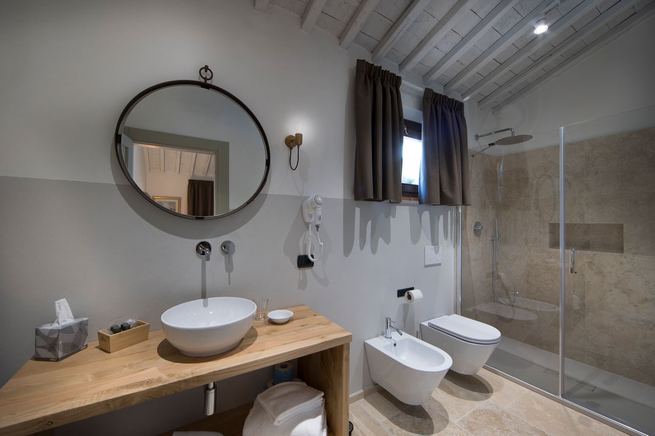 Un baño moderno con tocador de madera, dos lavamanos, un espejo grande, cabina de ducha y un inodoro.