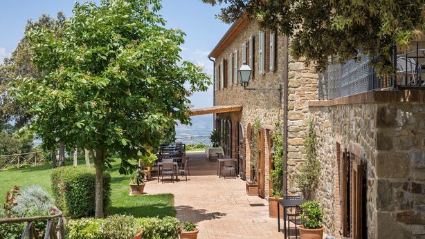 A stone building with outdoor seating and a view of the sea. - Agriturismo Podere l'Aione (Scansano)