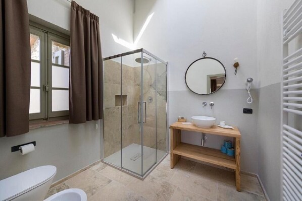 A bathroom with a glass-enclosed shower, a sink with a mirror, and a toilet.