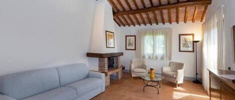 Una sala de estar con un sofá, dos sillones, una mesa de centro, una chimenea y techo de madera.