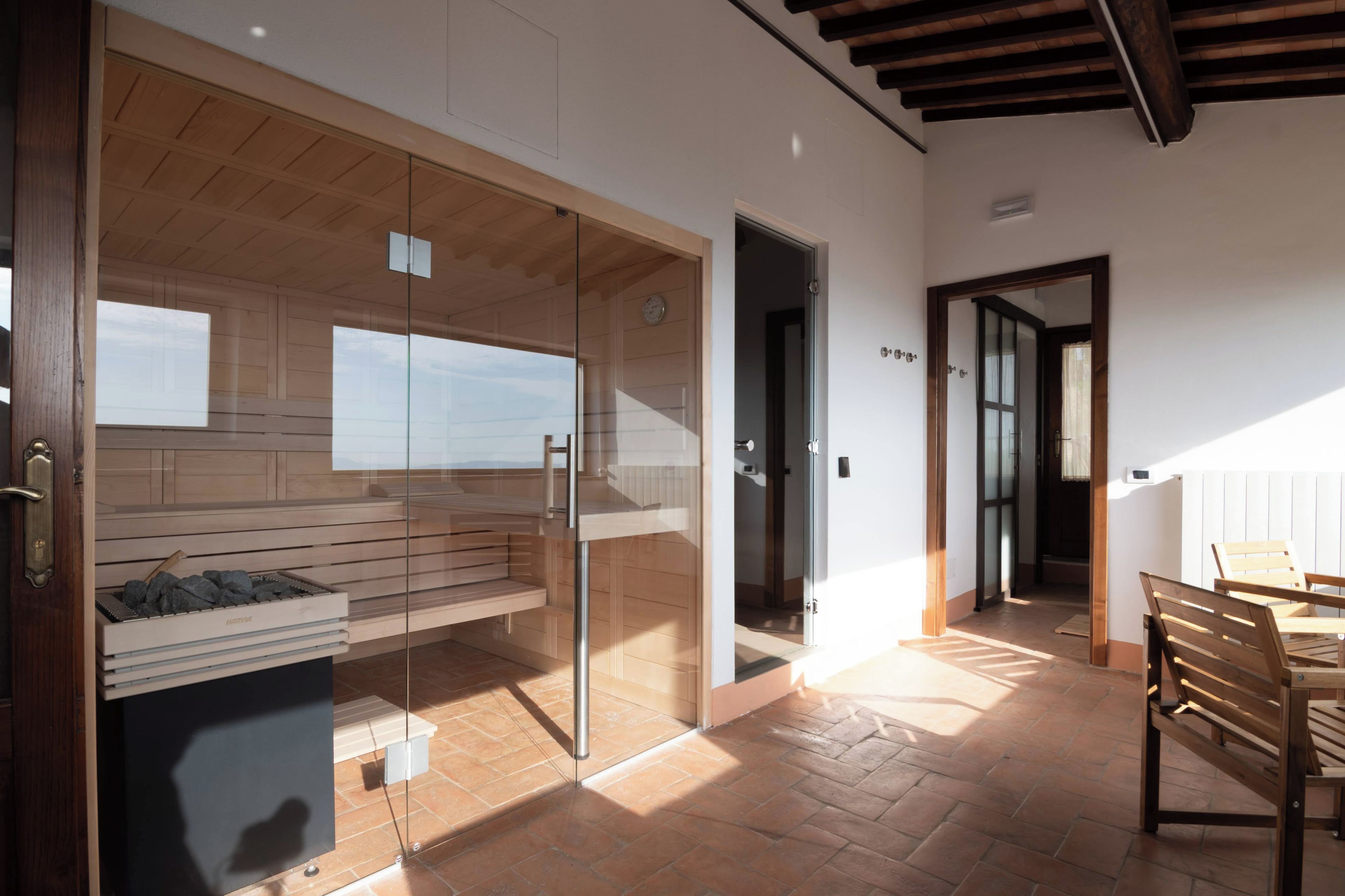 A modern interior with a glass partition, wooden flooring, and a dining area with chairs.